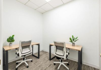 Bright internal two-person office suite with light wood desks and white ergonomic chairs.