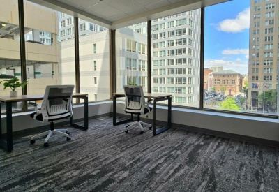 Corner office with expansive windows overlooking the city streets and neighboring skyscrapers.