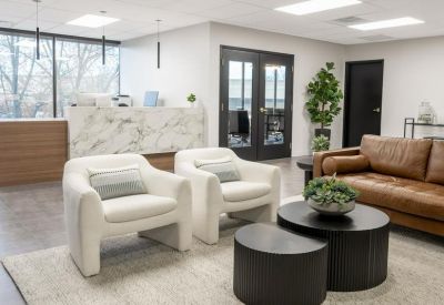Stylish reception area with a marble desk, white armchairs, and a warm leather sofa.