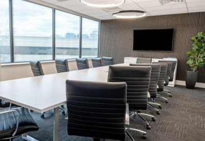 Large conference room with a long white table, ergonomic black chairs, and a wall-mounted TV.