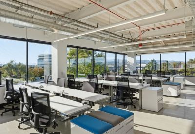 Bright open-plan workspace with white ergonomic desks and blue accent seating.