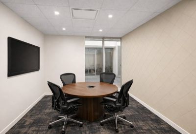 Private meeting room with a round wooden table and four ergonomic chairs.