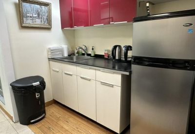Modern kitchenette with bright red upper cabinets, stainless steel appliances, and white base units.