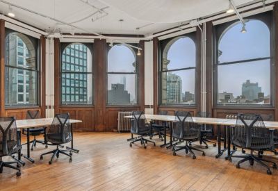 Spacious open office with arched windows and ergonomic chairs on wood floors.