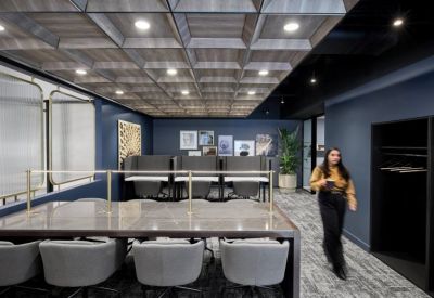 Spacious coworking area featuring a marble-topped table and private booths under a coffered wood ceiling.