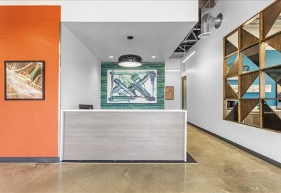 Modern reception desk area with a warm orange accent wall and artistic backdrop.