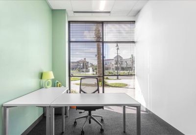 Modern corner office with a white L-shaped desk and a pale green feature wall.