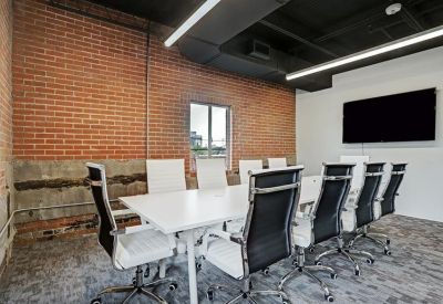 Modern meeting room featuring a white table, black chairs, and a brick accent wall.