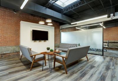 Lounge area with grey sofas, wood accents, and a large wall-mounted screen.