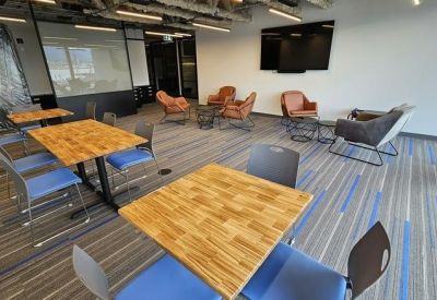 Informal breakout area with wooden tables, blue chairs, and comfortable leather armchairs.