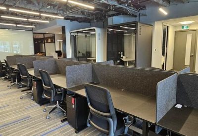 Open-plan workspace with rows of modern grey cubicles and black ergonomic chairs.