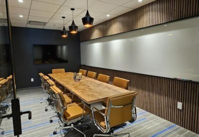 Executive boardroom with a light wood table, leather chairs, and wood-slat feature wall.