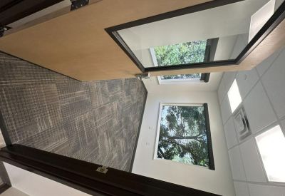 Private office suite with a wood door, carpeted floors, and views of pine trees through the window.