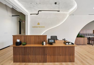 Warm reception area with a slatted wood desk, white curved walls, and Industrious branding.