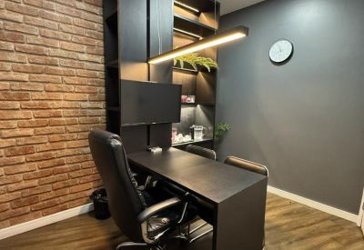 Private office featuring a brick accent wall, black desk, and ergonomic leather chair at Shopping Seaway.