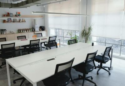 Clean white workstation rows with a small coffee station and pantry area in the background.