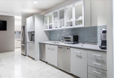 Spacious communal kitchen with white cabinetry, stainless steel appliances, and a tiled backsplash.