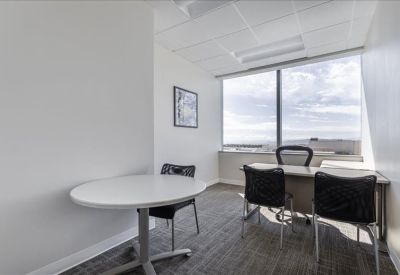 Bright private internal office with a round meeting table and a desk by the window.