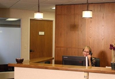 Wooden paneled reception desk with a staff member and overhead lighting.