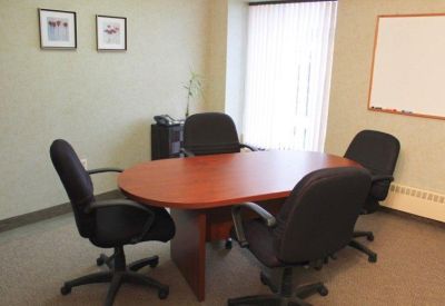 Small meeting room with an oval wooden table and four black chairs.