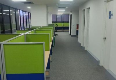 Long corridor of an open-plan office featuring green and blue upholstered privacy cubicles.