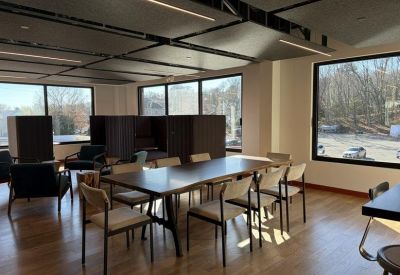 Modern meeting area with a long wooden table and stylish white chairs.