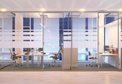 Modern open workspace separated by glass partitions under bright overhead lighting.