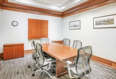 Professional meeting room with a large wooden table, mesh chairs, and classic wood paneling.