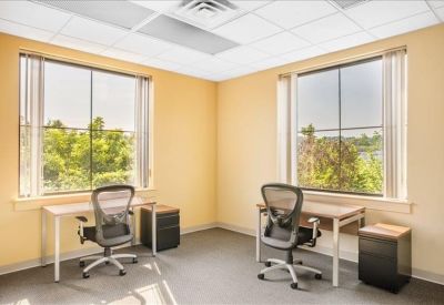 Spacious dual-occupancy office with two separate desks and chairs placed by large windows.