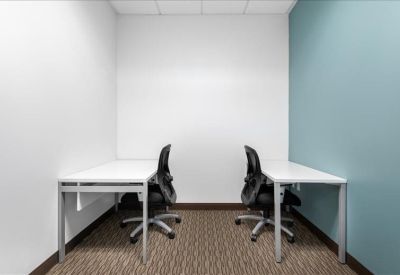 Two-person private office suite with white desks and a teal accent wall.