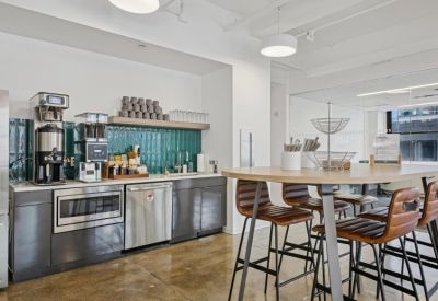 Shared kitchen area with teal tile backsplash and a high-top wooden table.