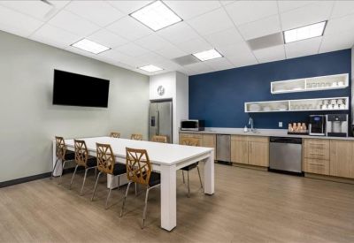 Modern communal kitchen and breakout area with a large white table and blue accent wall.