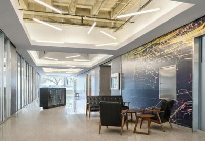 Spacious communal lobby with mid-century modern seating and a large geographic mural.