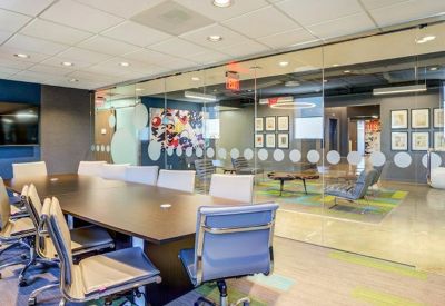 Modern conference room featuring a large dark wood table and glass partition walls.