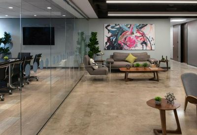 Lounge area with grey sofas, colorful abstract art, and a small meeting table.