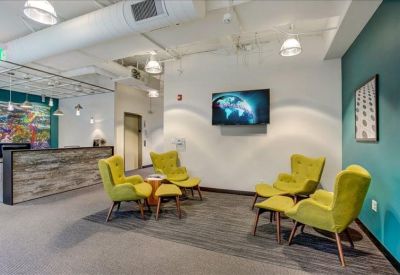 Lounge area with lime green armchairs and a wall-mounted television.