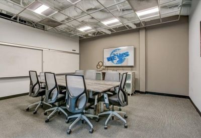 Modern conference room with a large table, mesh chairs, and whiteboard.