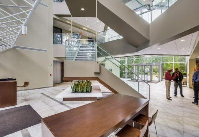 Spacious multi-level building atrium with central staircase and indoor plants.