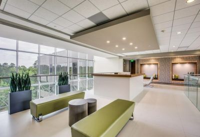 Modern reception lobby featuring green benches and a large window wall.