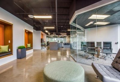 Coworking space featuring glass-walled offices and green velvet seating pods.