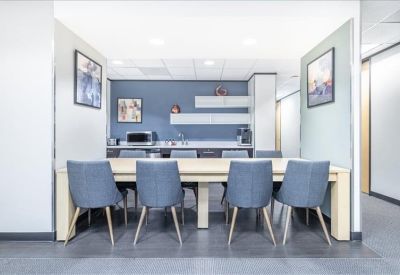 Communal kitchen and dining area with blue accent walls and modern blue chairs.