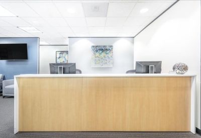 Light wood reception desk in a bright lobby area with abstract wall art.