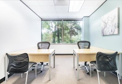 Bright four-person private office with large windows and mesh chairs.