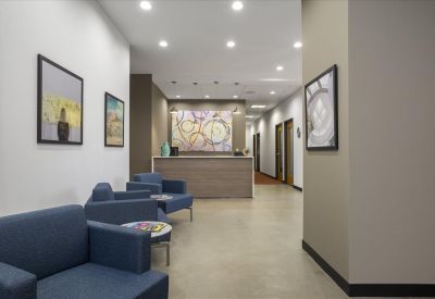 Spacious reception area at 2005 SE 192nd Avenue with blue armchairs, wall art, and a wooden front desk.