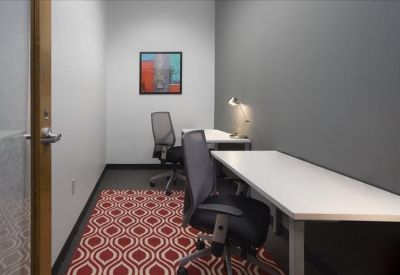 Private two-person office suite with white desks, ergonomic chairs, and a red patterned rug.
