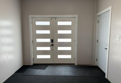 Interior view of white double doors with horizontal glass panes and black hardware.