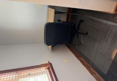 Private office nook with a black desk chair, wooden desk, and grey walls.