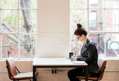 Individual workstation by a large window with views of brick buildings and mature trees.