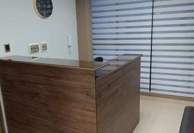 Wooden reception desk in a well-lit lobby with modern window blinds.