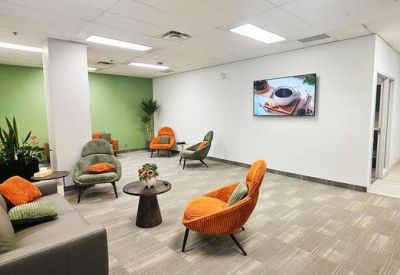 Modern lounge area with orange designer chairs and green feature wall.